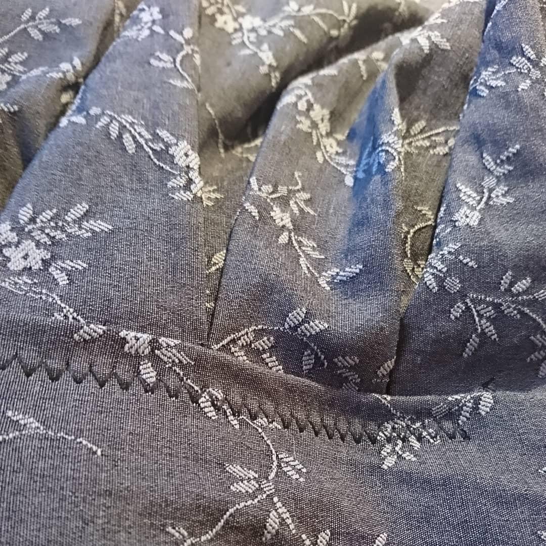 A close up on the stitching of a grey patterned fabric.