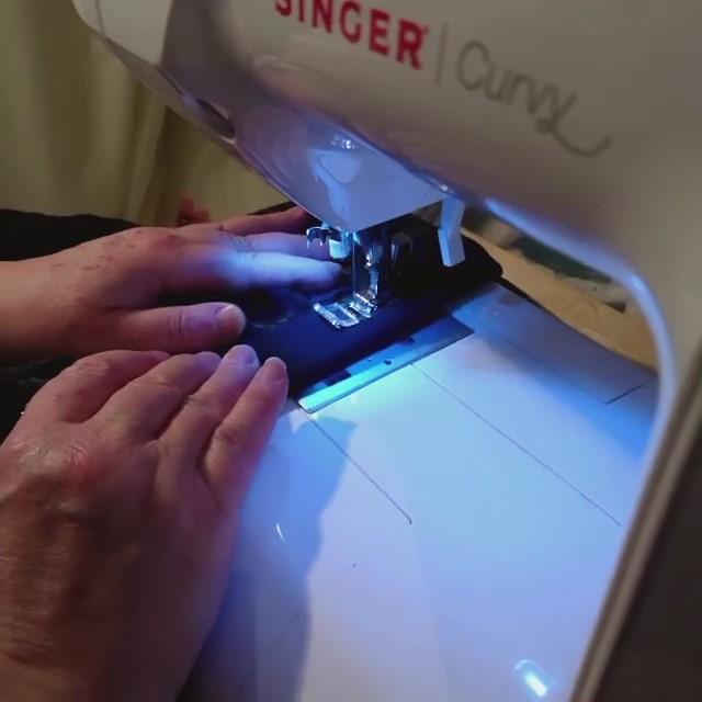 Hands feeding fabric into a sewing machine